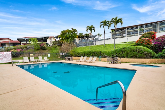 view of swimming pool featuring a hot tub and a patio area