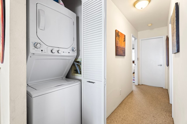 clothes washing area with stacked washer / drying machine and light colored carpet