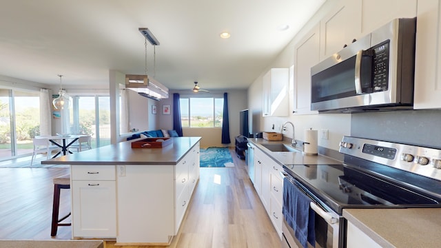 kitchen featuring sink, white cabinetry, a center island, pendant lighting, and stainless steel appliances