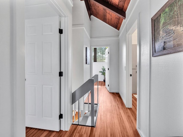 hallway featuring lofted ceiling with beams, light wood-type flooring, and wood ceiling