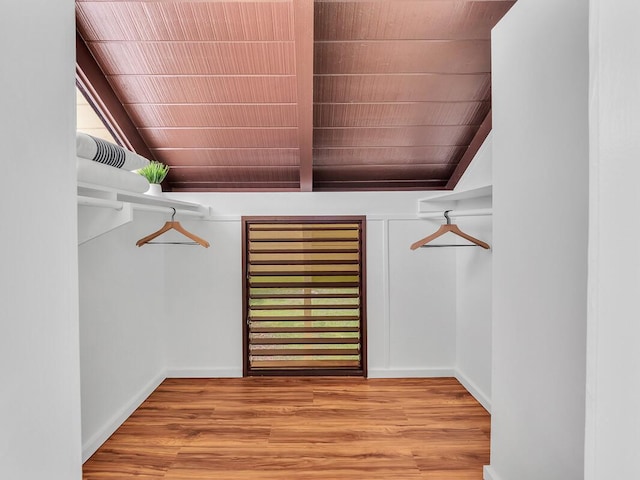 spacious closet with vaulted ceiling with beams and light wood-style flooring