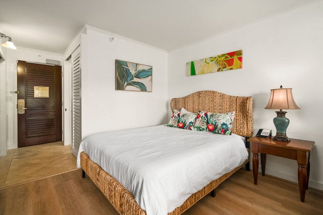 bedroom with hardwood / wood-style floors, crown molding, and a closet