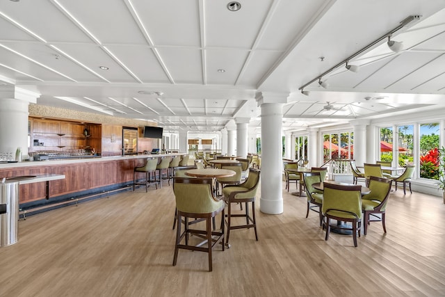 dining room with track lighting, light hardwood / wood-style floors, and ornate columns