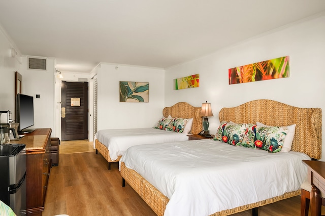 bedroom featuring hardwood / wood-style floors, crown molding, and a closet