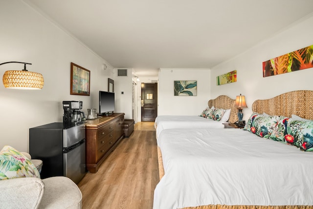 bedroom featuring stainless steel refrigerator and light hardwood / wood-style floors