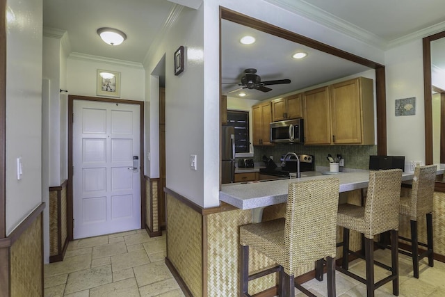 kitchen with crown molding, a kitchen breakfast bar, kitchen peninsula, ceiling fan, and stainless steel appliances