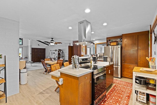 kitchen with island exhaust hood, a center island, ceiling fan, stainless steel appliances, and light hardwood / wood-style floors