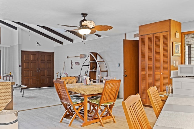 dining room featuring ceiling fan, light wood-type flooring, and vaulted ceiling with beams