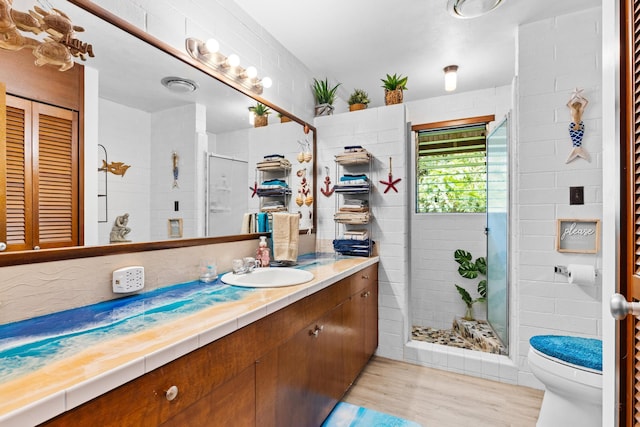 bathroom with vanity, hardwood / wood-style flooring, a shower with door, and toilet