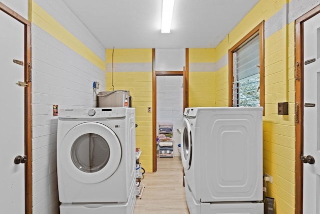 laundry area with tile walls, washer and dryer, and light wood-type flooring