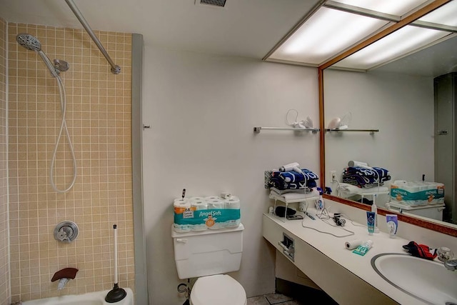 full bathroom with tiled shower / bath, vanity, and toilet