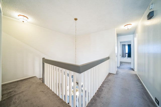 hall featuring carpet floors and a textured ceiling