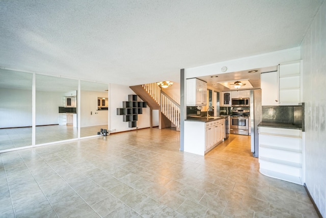 kitchen featuring sink, backsplash, white cabinets, a chandelier, and stainless steel appliances