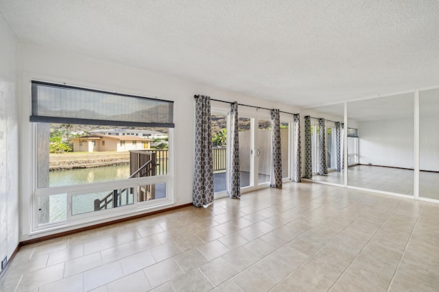 unfurnished room featuring a water view, plenty of natural light, and a textured ceiling