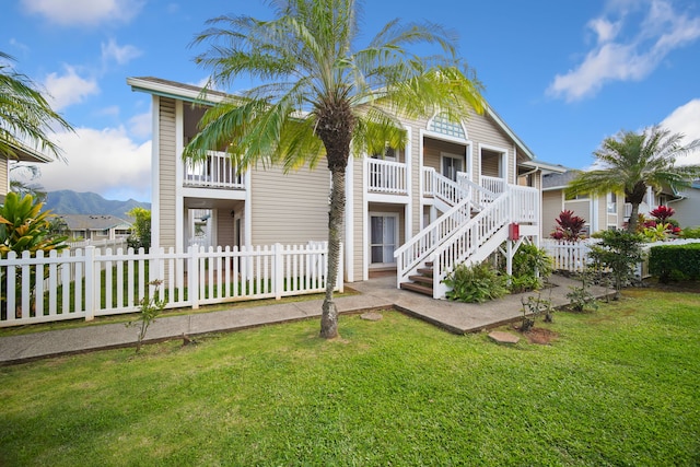 rear view of house featuring a porch, a mountain view, and a yard