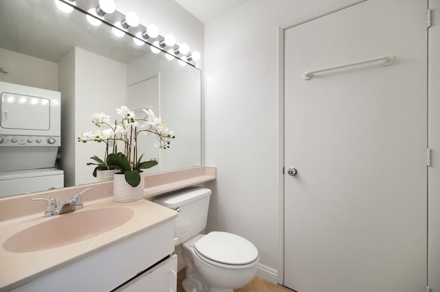 bathroom featuring stacked washer / dryer, vanity, and toilet