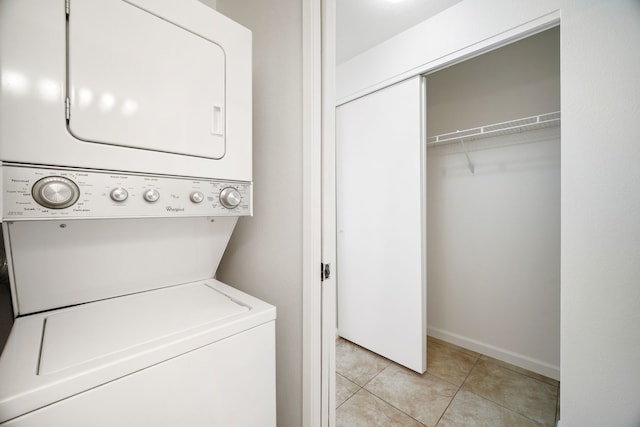 laundry area featuring light tile patterned floors and stacked washing maching and dryer