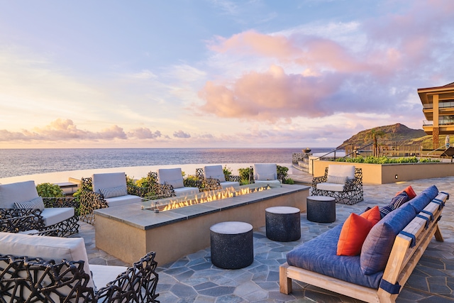 patio terrace at dusk with a water view and an outdoor fire pit