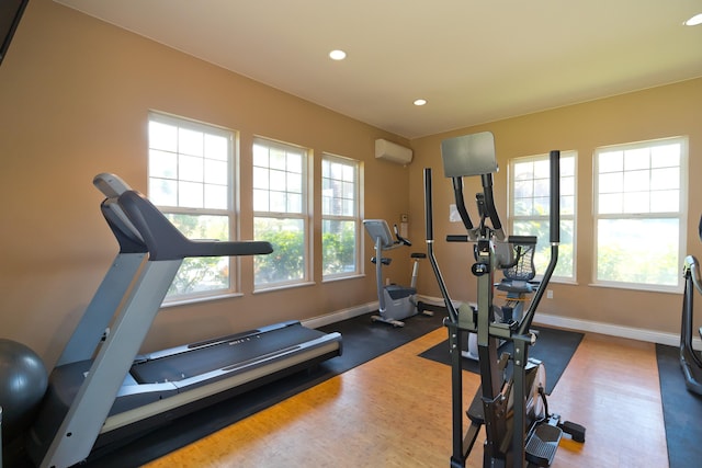 exercise room with a wall mounted air conditioner, dark hardwood / wood-style floors, and plenty of natural light