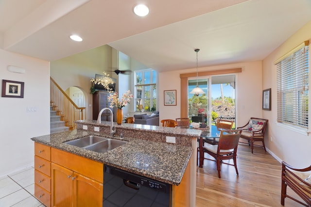 kitchen featuring pendant lighting, dishwasher, sink, a kitchen island with sink, and light hardwood / wood-style flooring