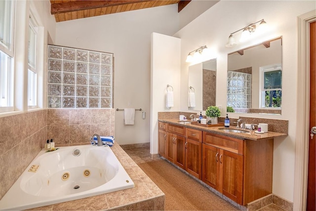 bathroom with a wealth of natural light, lofted ceiling with beams, vanity, wood ceiling, and tiled tub