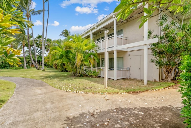 view of side of home featuring a balcony and a yard