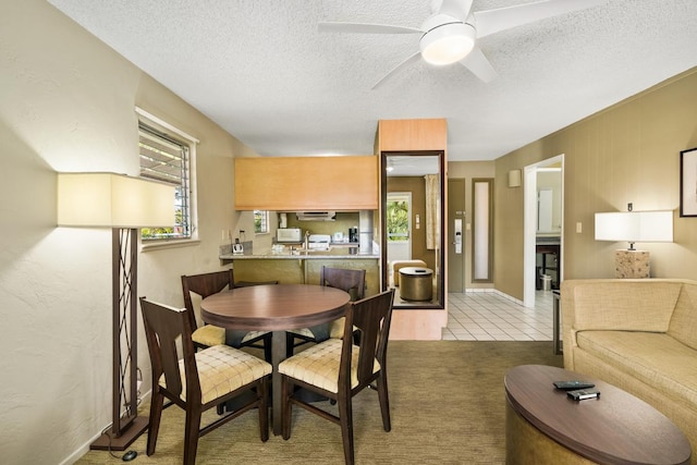 dining space with ceiling fan, light colored carpet, and a textured ceiling