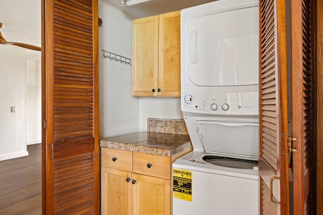 laundry area featuring dark wood finished floors, stacked washer / drying machine, and a textured wall