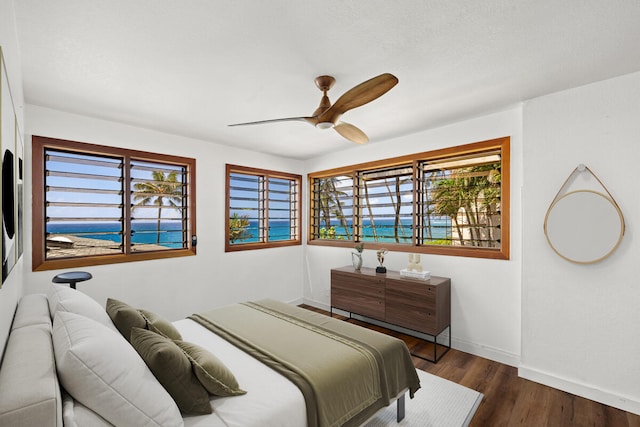 bedroom with multiple windows, wood finished floors, baseboards, and a ceiling fan