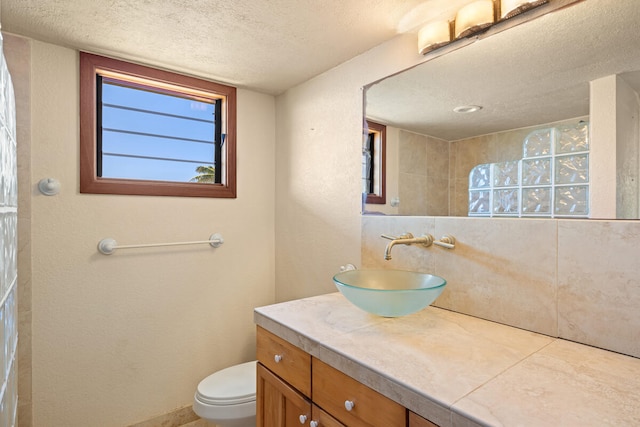 bathroom with a shower, toilet, vanity, and a textured ceiling