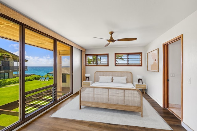bedroom featuring dark wood finished floors, baseboards, a water view, and ceiling fan