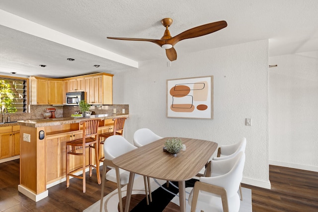 dining room featuring dark wood-style flooring, a textured wall, baseboards, a textured ceiling, and ceiling fan