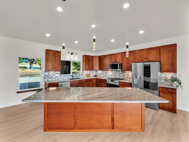 kitchen featuring a spacious island, stainless steel appliances, light stone countertops, and pendant lighting