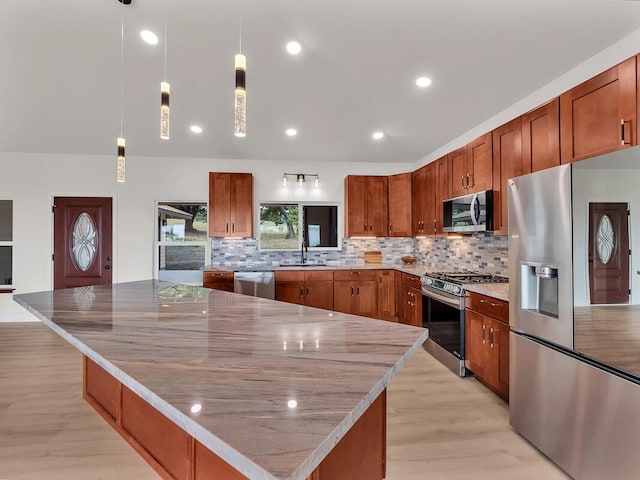 kitchen featuring stainless steel appliances, pendant lighting, decorative backsplash, and a spacious island