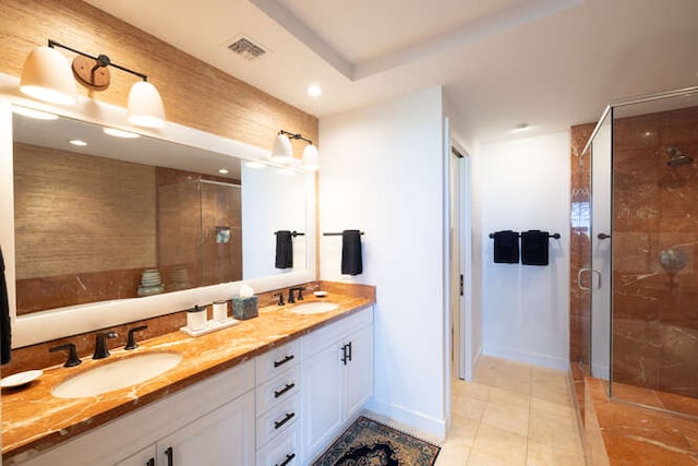 full bath with double vanity, a stall shower, baseboards, and a sink