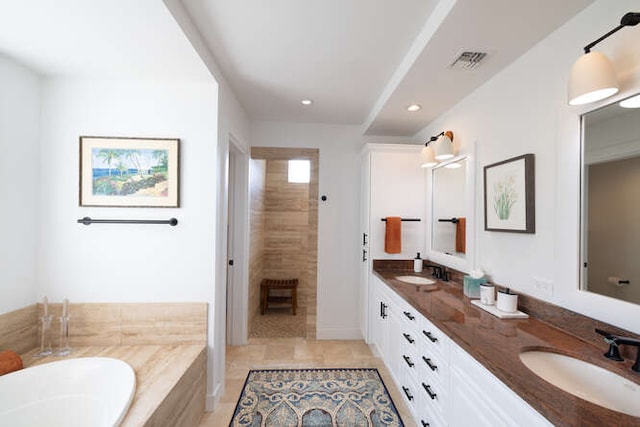 bathroom with double vanity, a bathing tub, a sink, and visible vents