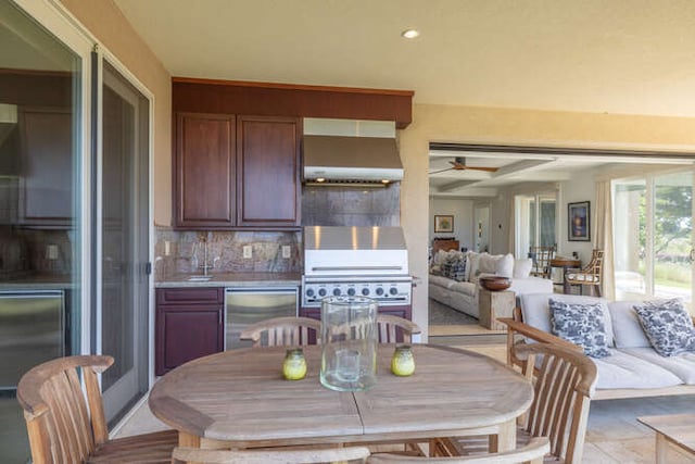 kitchen with ceiling fan, wall chimney exhaust hood, open floor plan, refrigerator, and backsplash