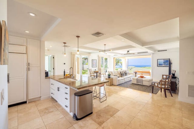 kitchen with visible vents, white cabinets, a sink, and a peninsula