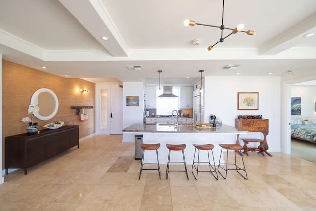 kitchen featuring a breakfast bar, a large island, recessed lighting, an accent wall, and wall chimney range hood