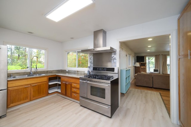 kitchen with wall chimney exhaust hood, stainless steel appliances, sink, and light hardwood / wood-style flooring