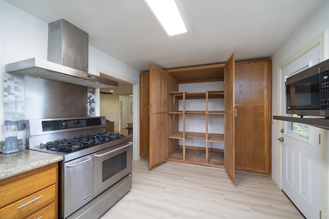 kitchen with stainless steel appliances, decorative backsplash, light hardwood / wood-style floors, and range hood