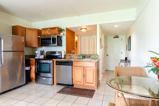 kitchen featuring sink, light tile patterned floors, light stone countertops, and appliances with stainless steel finishes