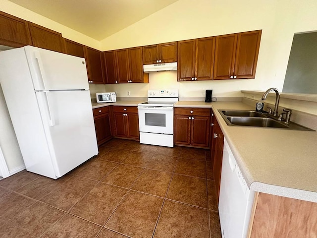 kitchen with sink, white appliances, vaulted ceiling, and dark tile patterned flooring