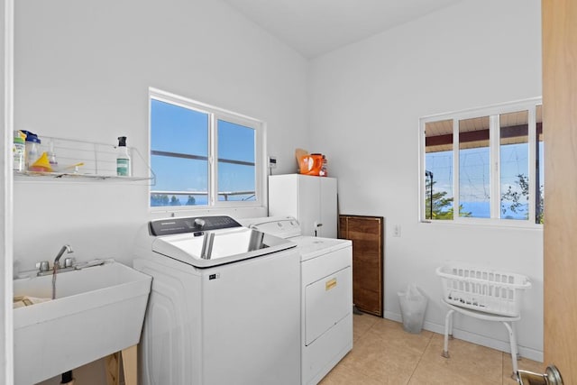 clothes washing area featuring sink, washer and clothes dryer, and light tile patterned flooring