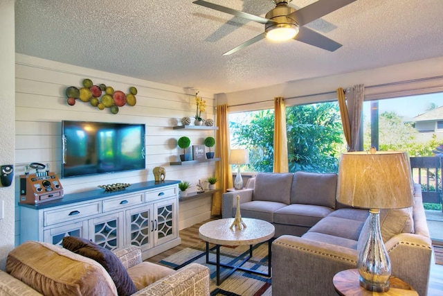 living room with ceiling fan, a textured ceiling, a wealth of natural light, and wood-type flooring