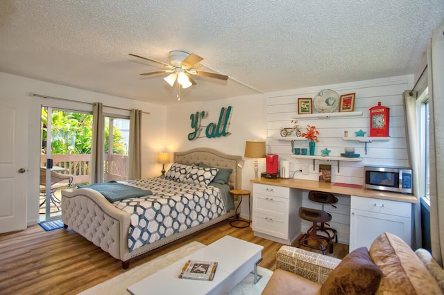 bedroom with ceiling fan, access to exterior, light hardwood / wood-style floors, and a textured ceiling