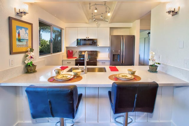 kitchen featuring white cabinetry, black appliances, kitchen peninsula, and a kitchen bar