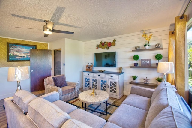 living room with ceiling fan, hardwood / wood-style floors, and a textured ceiling