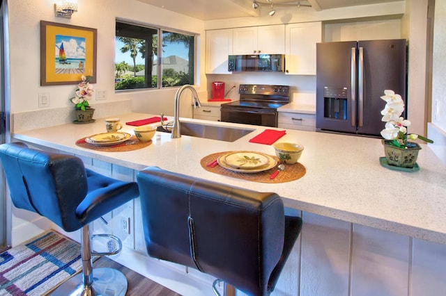 kitchen with range with electric cooktop, sink, white cabinets, a kitchen bar, and stainless steel fridge with ice dispenser