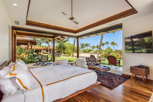 bedroom featuring floor to ceiling windows, hardwood / wood-style flooring, access to outside, and a raised ceiling